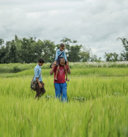 Person affected by leprosy Gobal with his children walking through the field